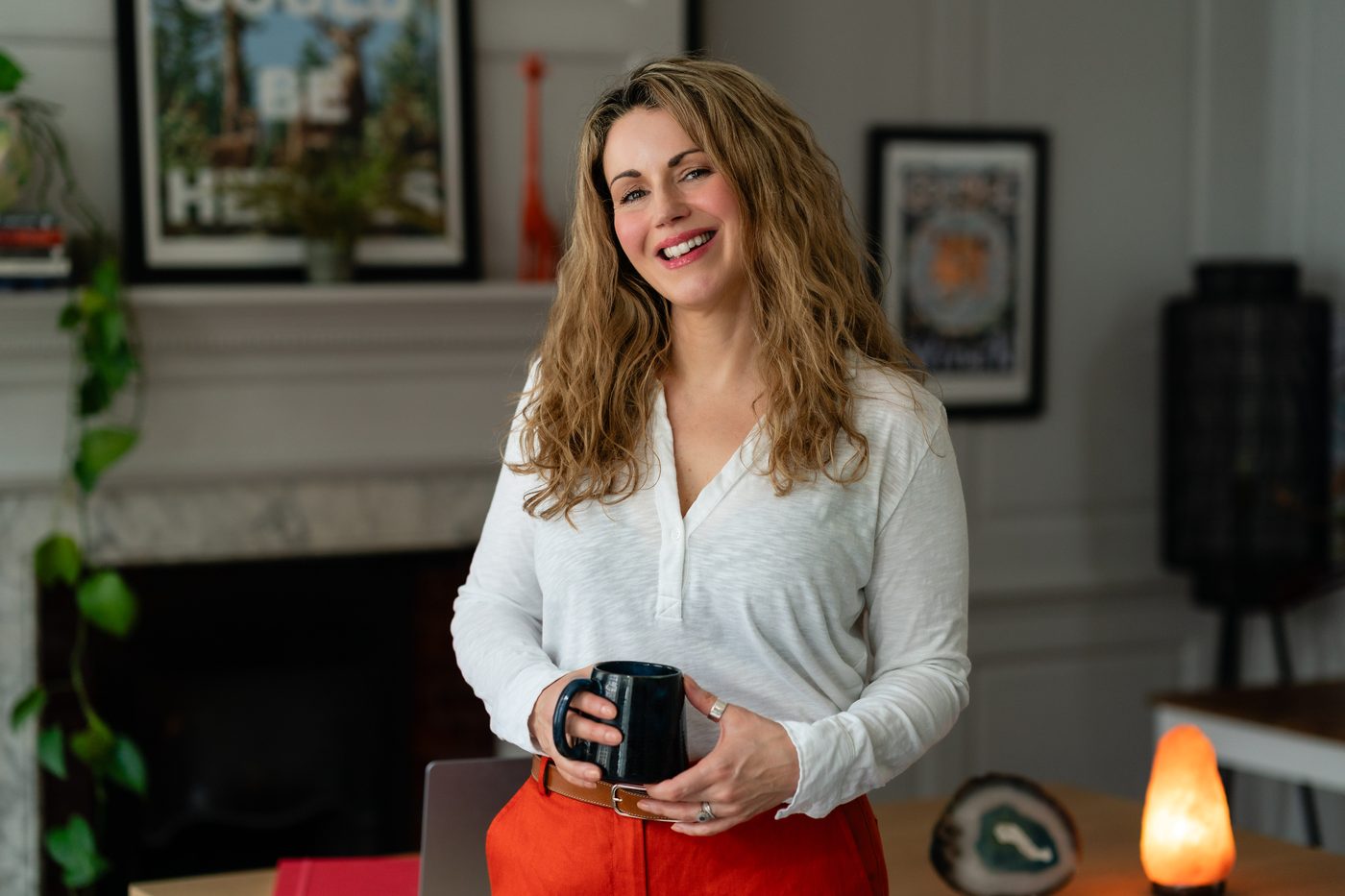Karlina Jordan smiling warmly, holding a mug in her sitting room